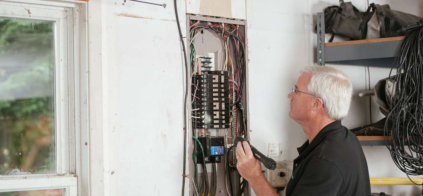 An electrician testing a residential breaker panel