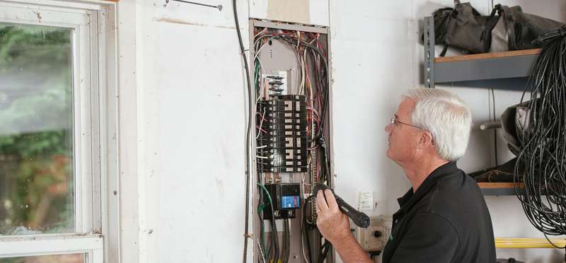 An electrician testing a residential breaker panel