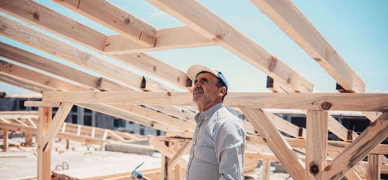 A contractor looking up at new timber roof framing