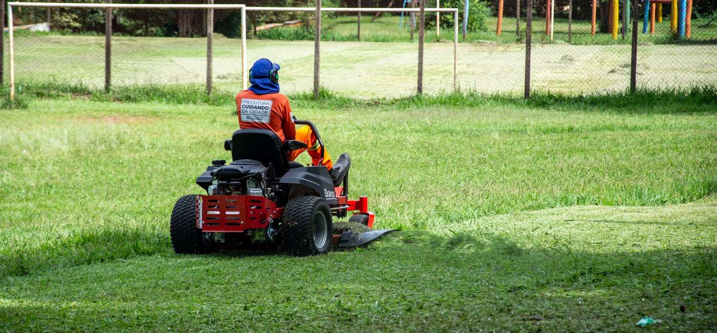 A groundsman on a riding mower cutting a large lawn